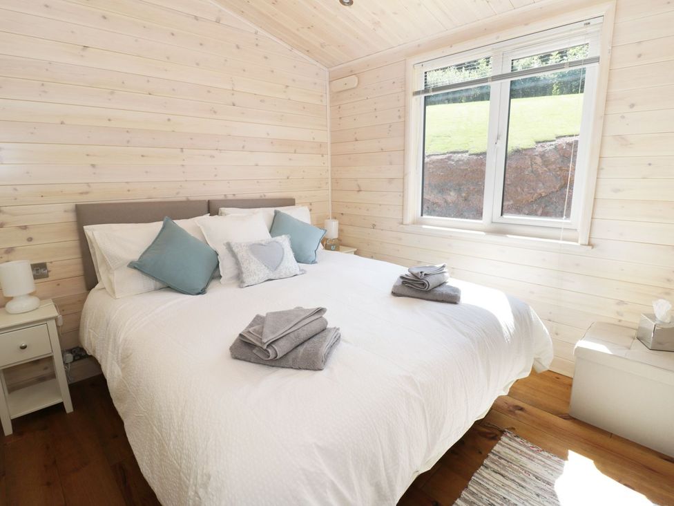 A bedroom with a bed and bedside table at Kingfisher in Ross-on-Wye