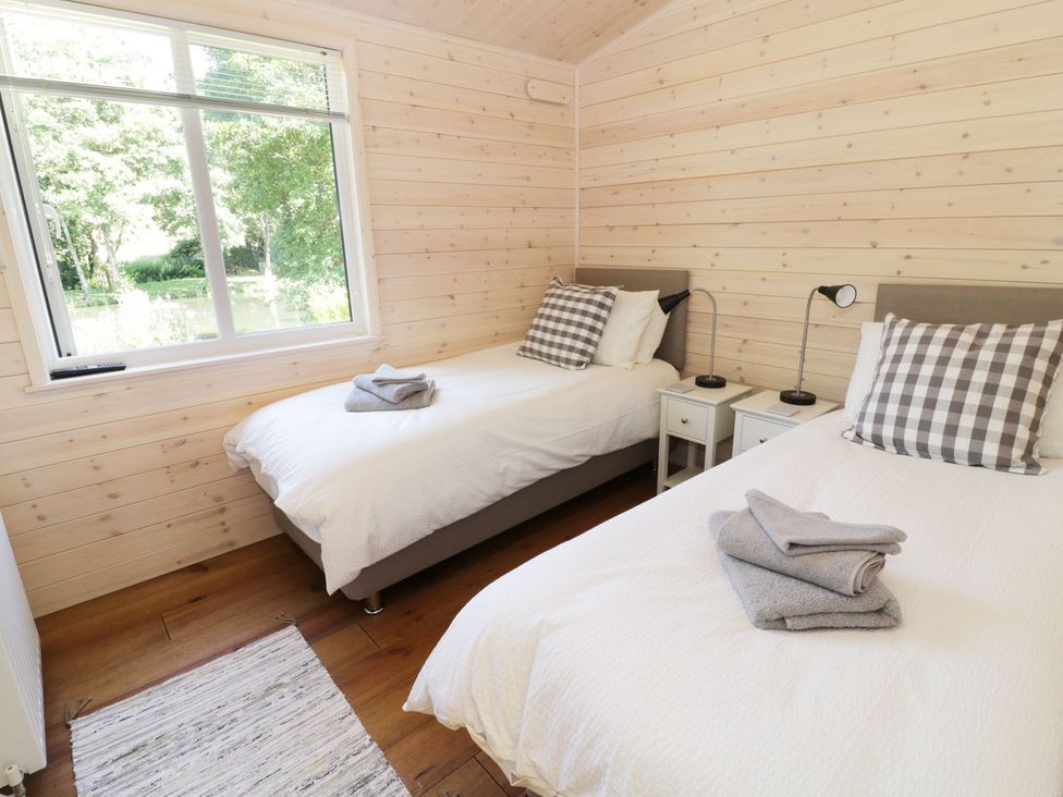 A bedroom with two beds and a window at Kingfisher in Ross-on-Wye