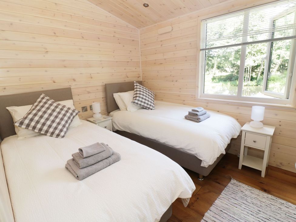 A bedroom with twin beds and a window at Kingfisher in Ross-on-Wye