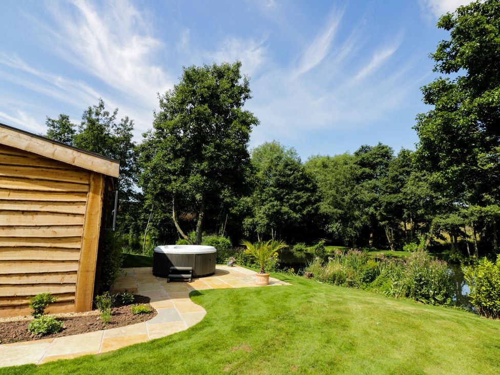 A garden with a hot tub next to a wooden building at Kingfisher in Ross-on-Wye