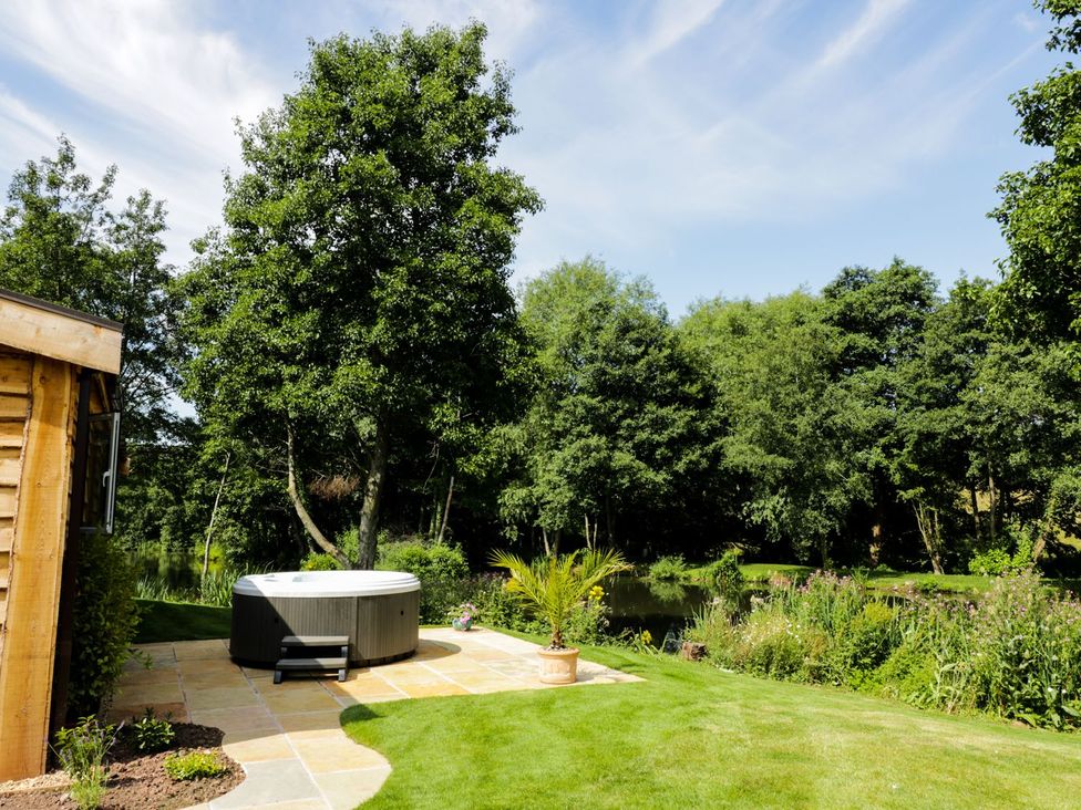 A garden with a hot tub and a wooden shed at Kingfisher in Ross-on-Wye