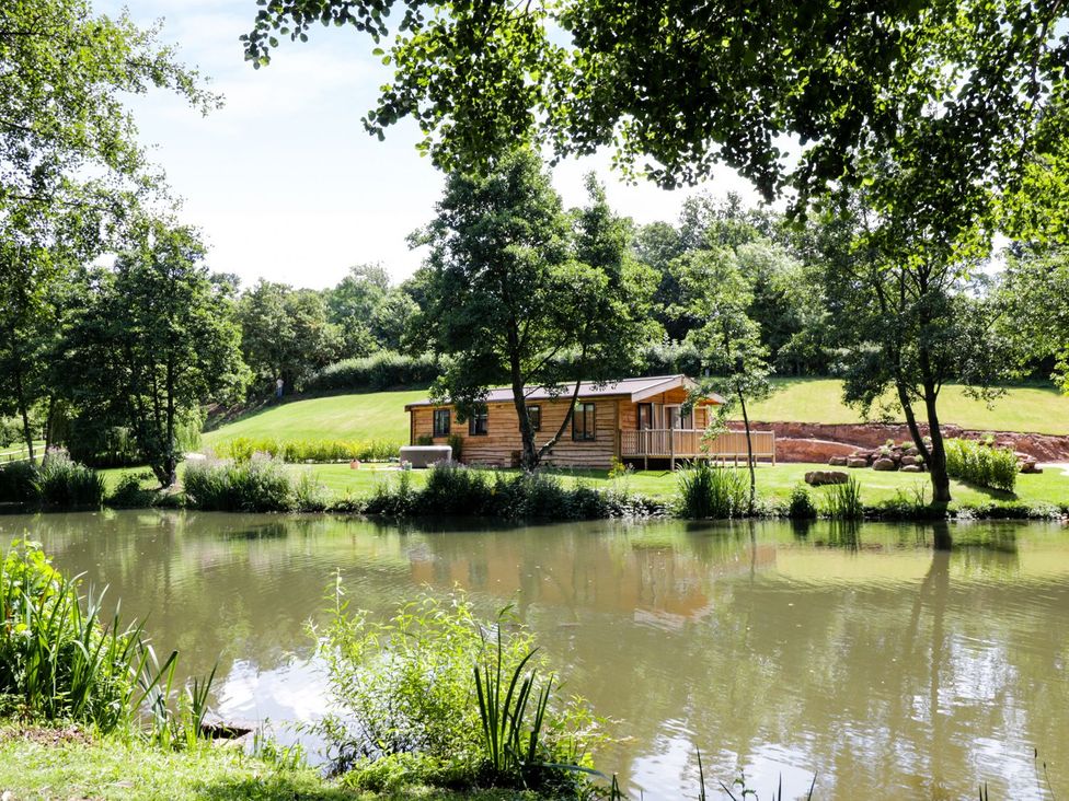 A cabin by a lake surrounded by trees at Kingfisher in Ross-on-Wye