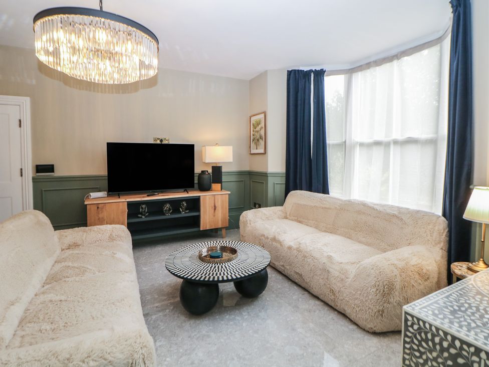 A living room with a television and two sofas at The Pavillon Suite in Buxton