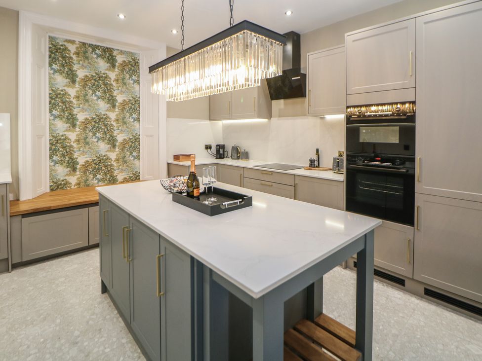 A kitchen with an island, light fixture, and oven at The Pavillon Suite in Buxton
