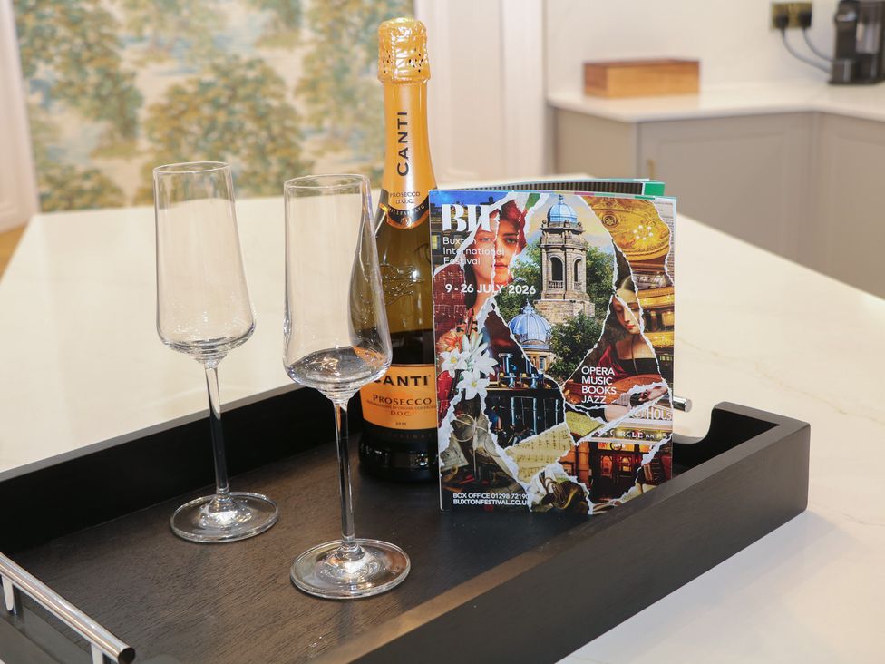 A champagne bottle, two glasses, and a magazine on a tray at The Pavillon Suite in Buxton