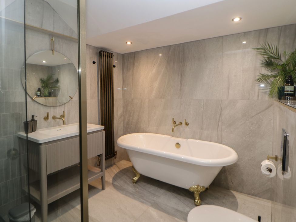 A bathroom with a bathtub, sink, and mirror at The Pavillon Suite in Buxton