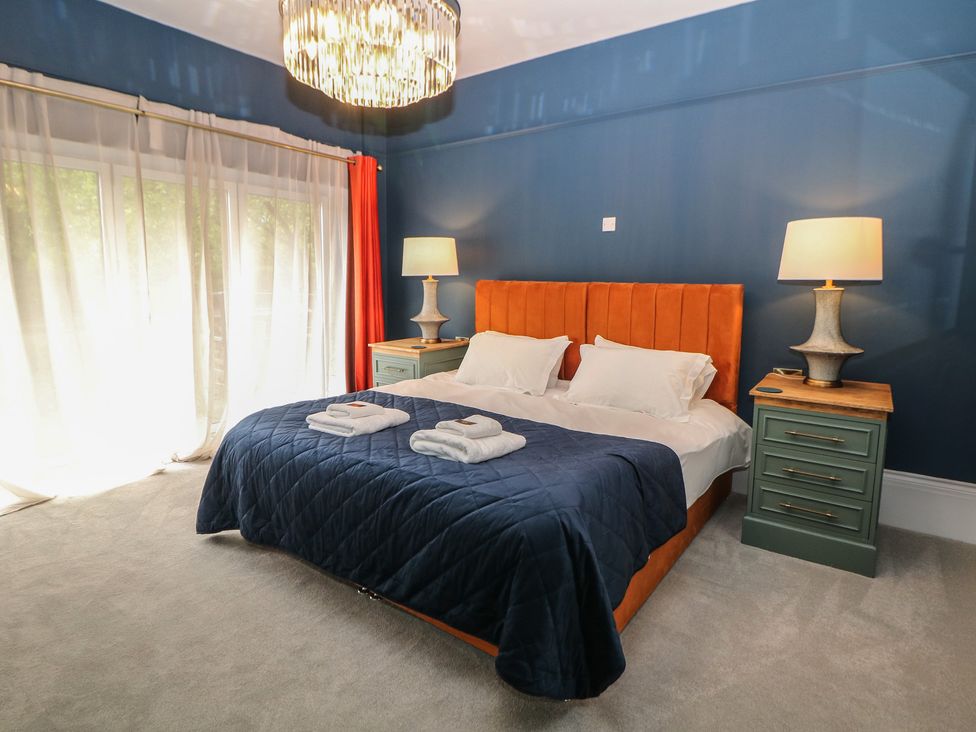 A bedroom with a bed and nightstand at The Pavillon Suite in Buxton
