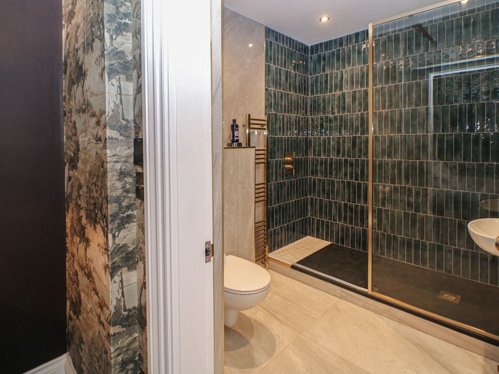 A bathroom with a toilet, sink, shower, and towel rack at The Pavillon Suite in Buxton