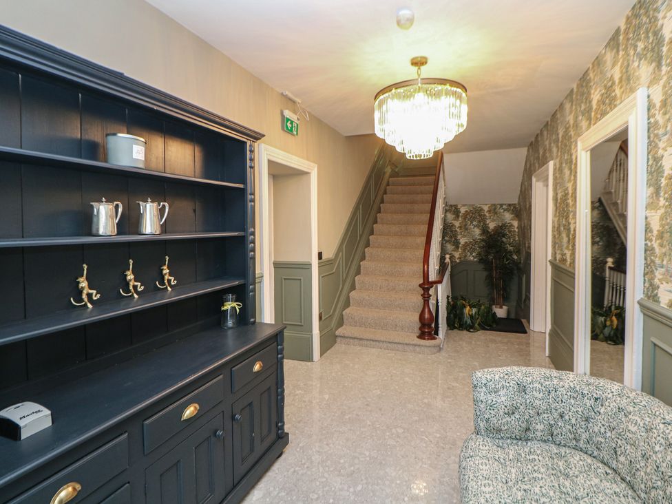 A hallway with a staircase and a shelf at The Pavillon Suite in Buxton