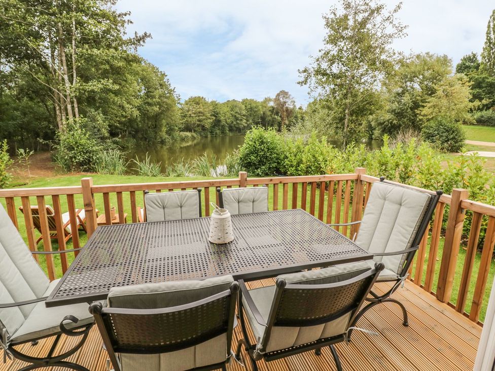 An outdoor seating area with a table and chairs overlooking a lake at Mallard in Ross-on-Wye
