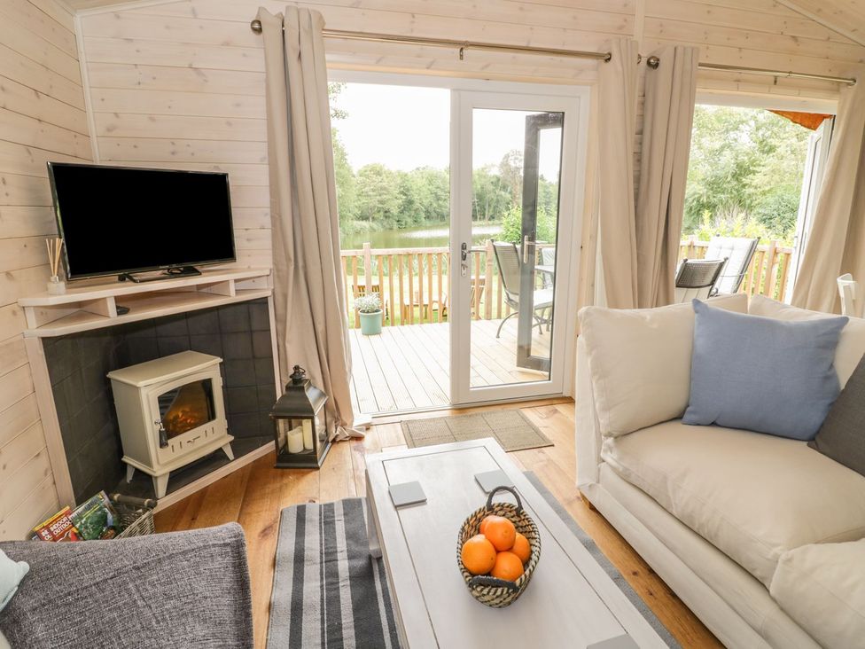 A living room with a television, sofa, and coffee table at Mallard in Ross-on-Wye