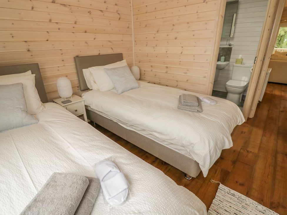 A bedroom with two beds and a bathroom door at Mallard in Ross-on-Wye
