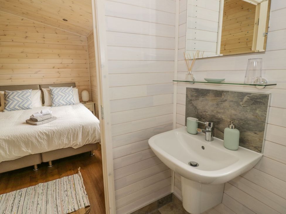 A bedroom with a bed, bedside table, and sink at Mallard, Ross-on-Wye