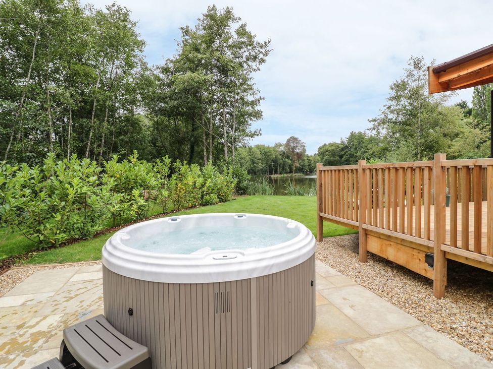A hot tub and wooden decking in a garden at Mallard Ross-on-Wye