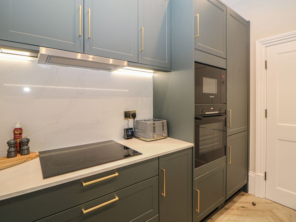 A kitchen with cabinets, oven, microwave, and induction cooktop at The Haddon Suite in Buxton