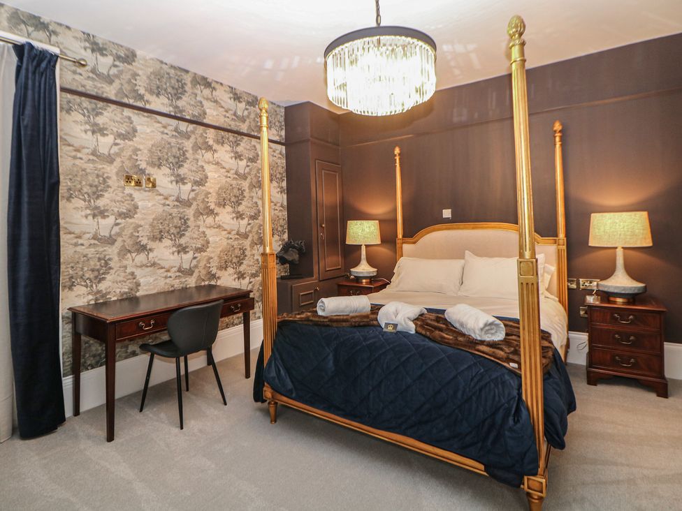 A bedroom with a four-poster bed and desk at The Haddon Suite in Buxton