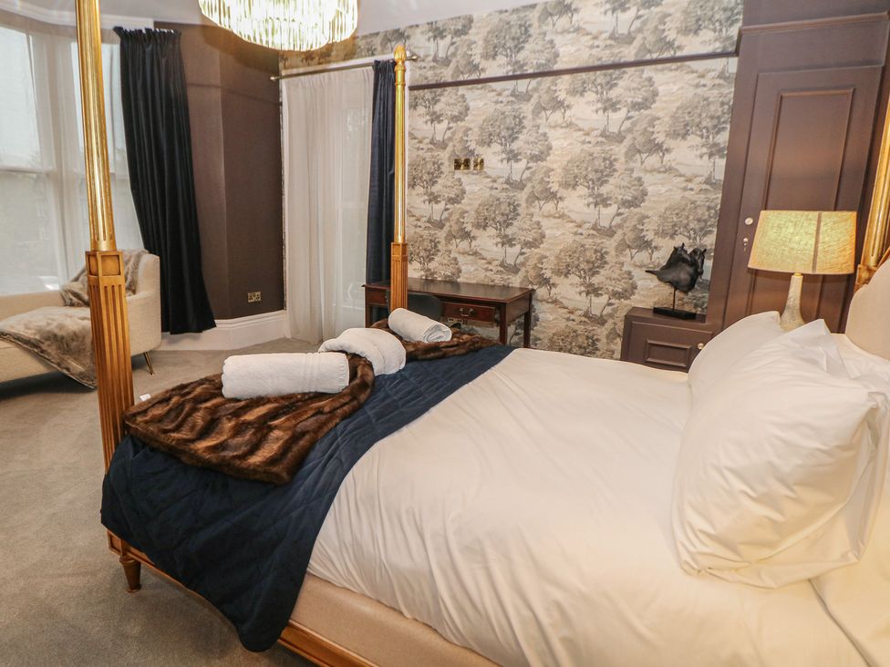 A bedroom with a bed and armchair at The Haddon Suite in Buxton