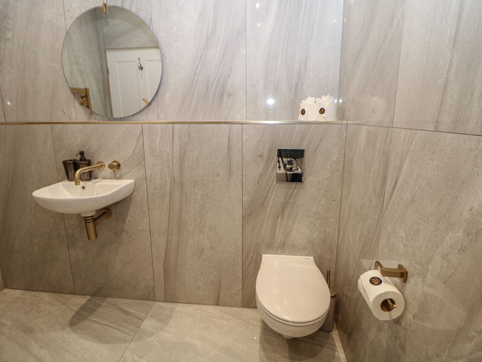 A bathroom with a sink, toilet, and mirror at The Haddon Suite in Buxton