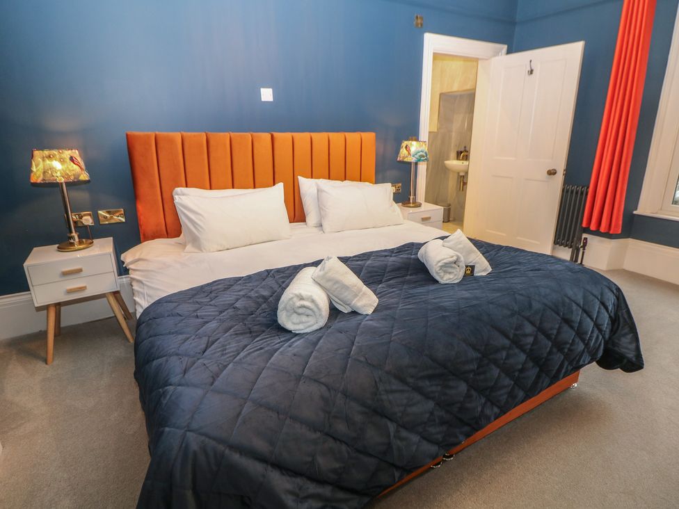 A bedroom with an orange bed and white pillows at The Haddon Suite in Buxton