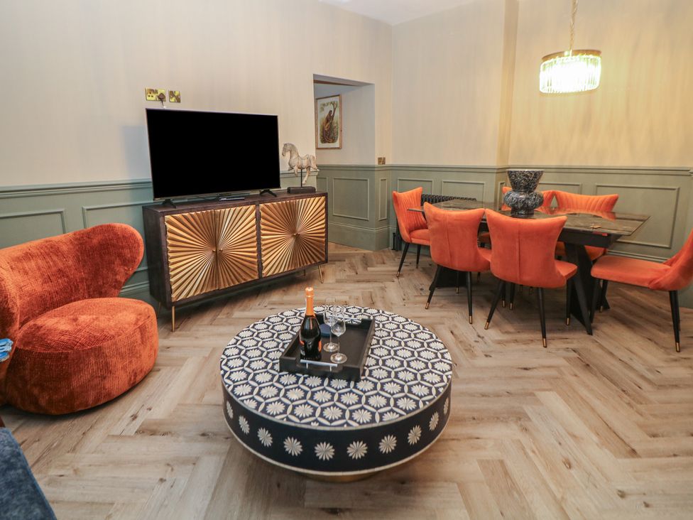 A living room with a television and dining area at The Haddon Suite in Buxton