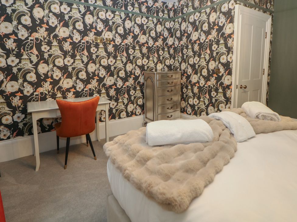 A bedroom with a bed and a vanity table at The Chatsworth Suite in Buxton