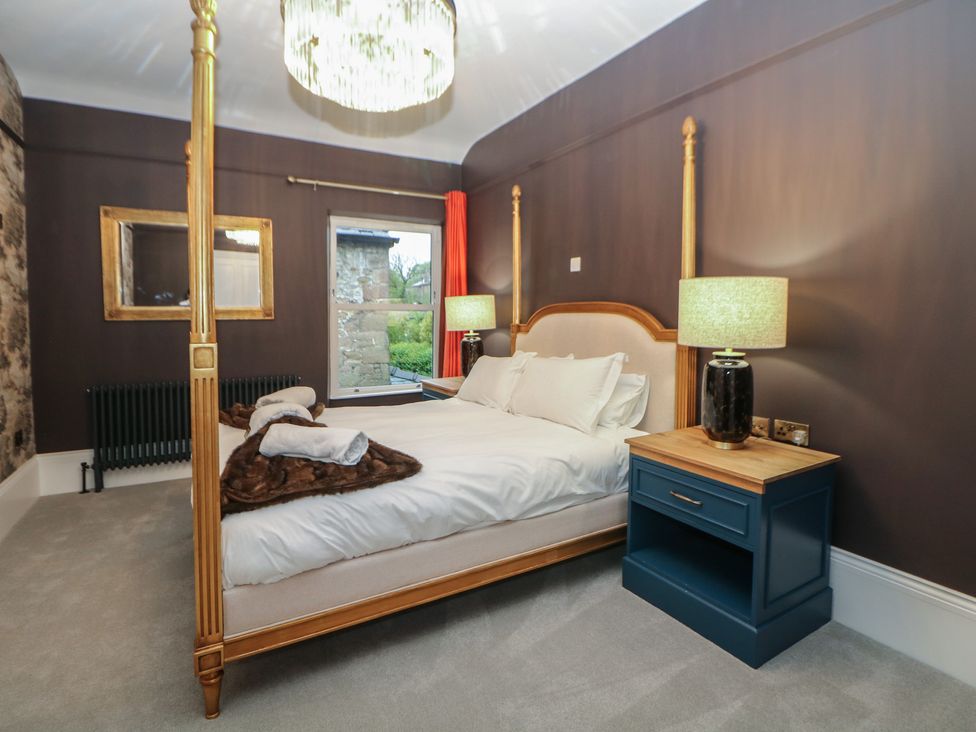 A bedroom with a four-poster bed and bedside lamps at The Chatsworth Suite in Buxton