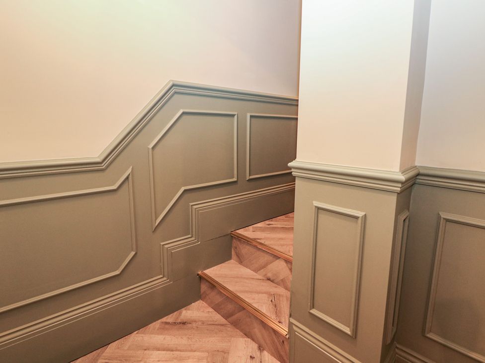 A staircase with wooden stairs and wall paneling at The Chatsworth Suite in Buxton