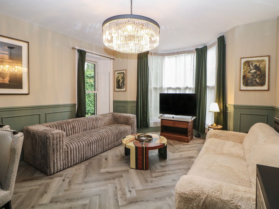 A living room with a sofa, coffee table, and television at The Devonshire Suite in Buxton