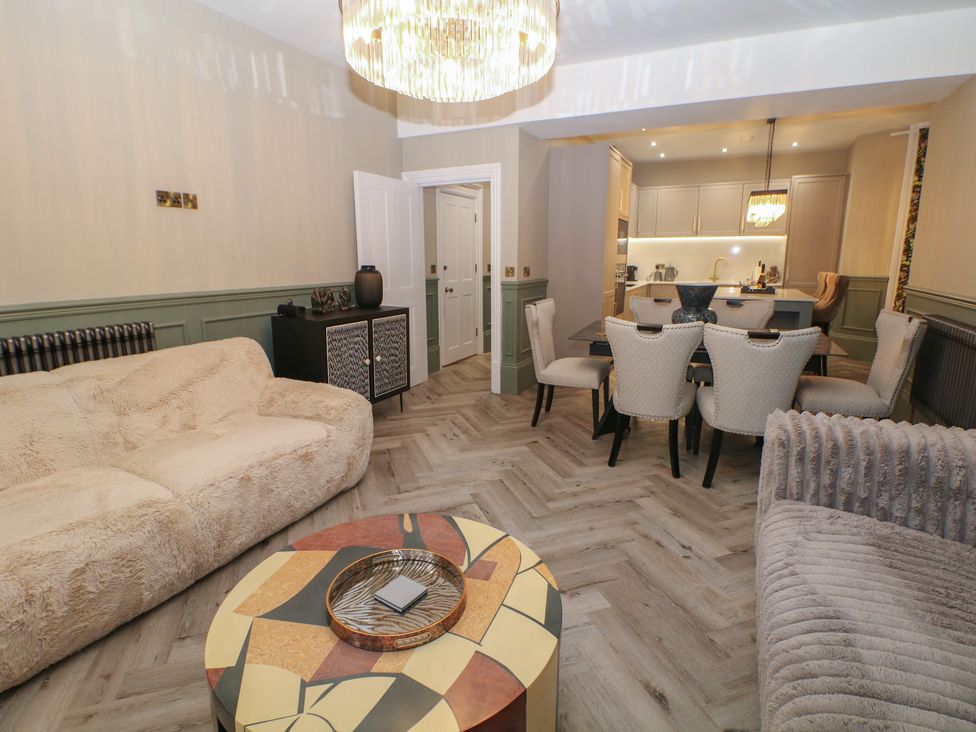 A living room with a sofa and dining area at The Devonshire Suite in Buxton