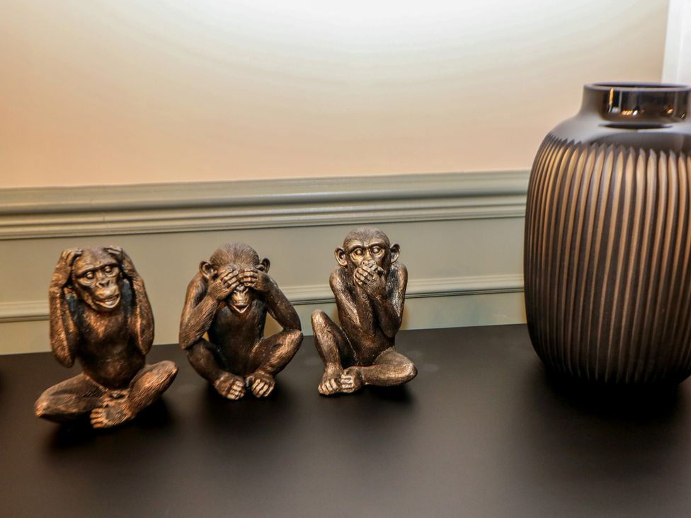 A living room with monkey statues and a decorative vase at The Devonshire Suite in Buxton