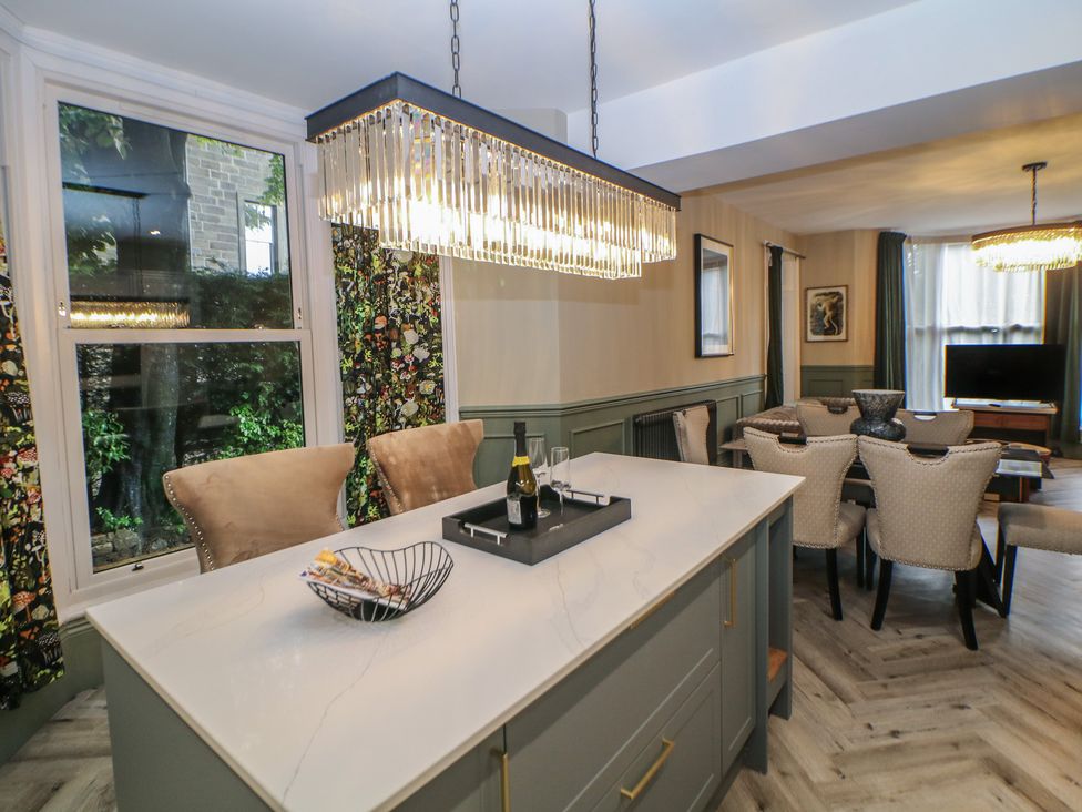 A dining room with an island countertop and dining table at The Devonshire Suite in Buxton