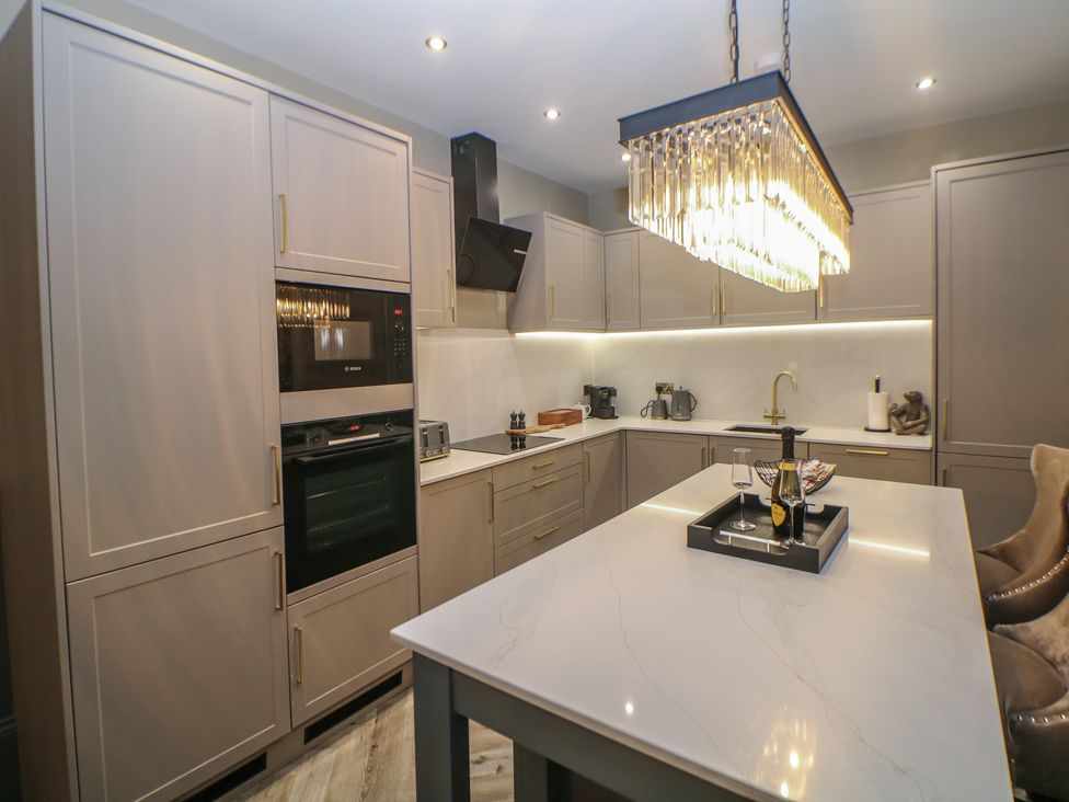 A kitchen with cabinets and an island at The Devonshire Suite in Buxton