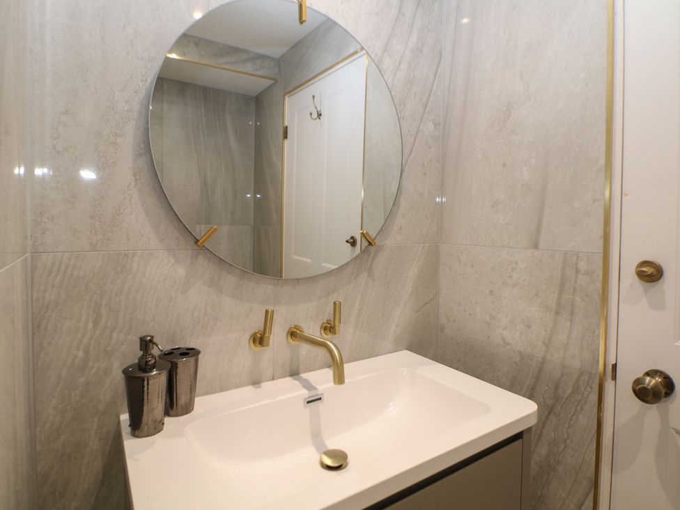 A bathroom with sink and round mirror at The Devonshire Suite in Buxton