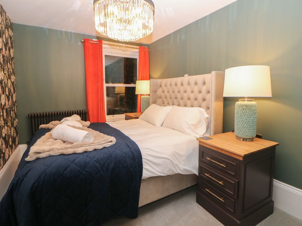A bedroom with a bed and bedside table at The Devonshire Suite in Buxton
