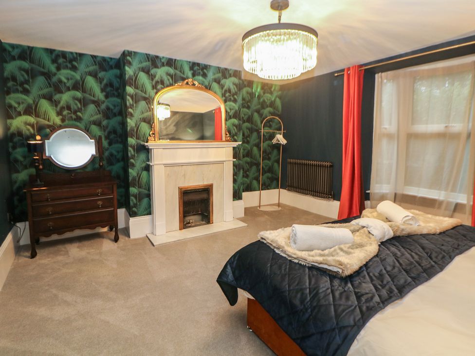 A bedroom with a bed and a dresser at The Devonshire Suite in Buxton