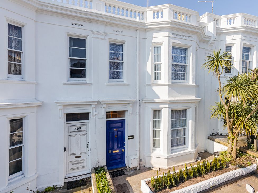 An exterior view of a white building with blue door and windows at Palm Villa in Torquay