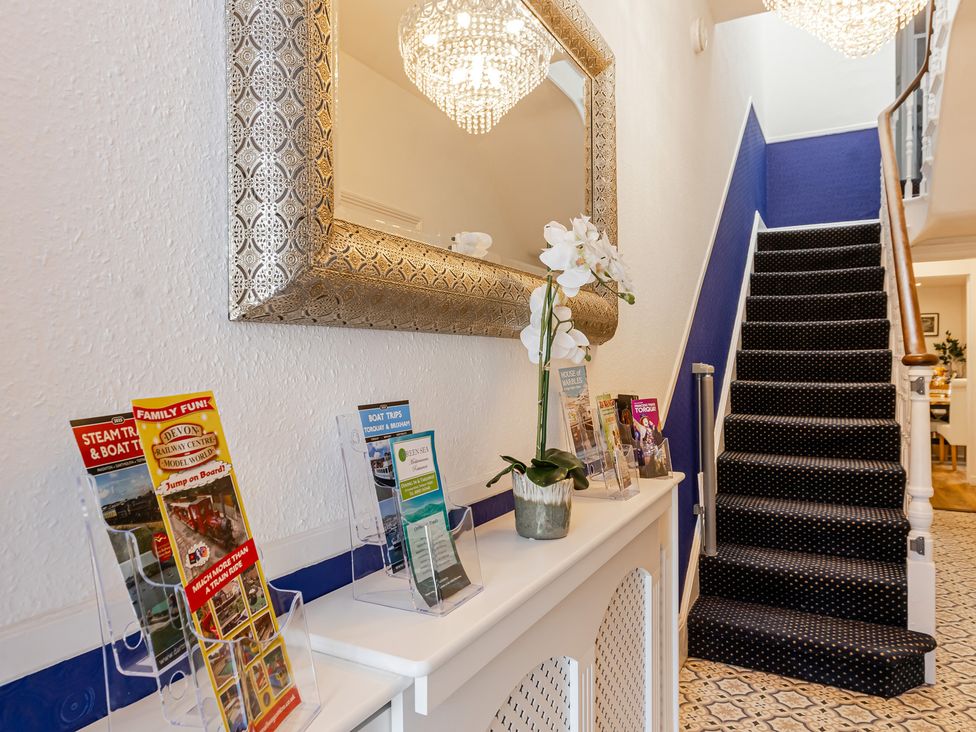 A hallway with a mirror and display of brochures at Palm Villa Torquay