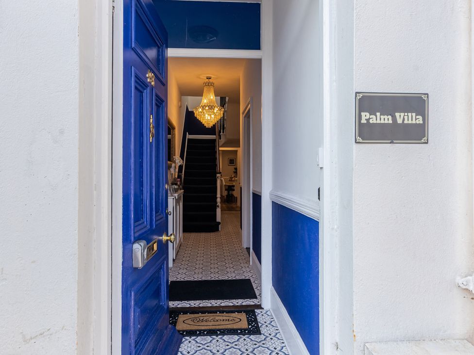 An entrance hall with a chandelier and a staircase at Palm Villa in Torquay