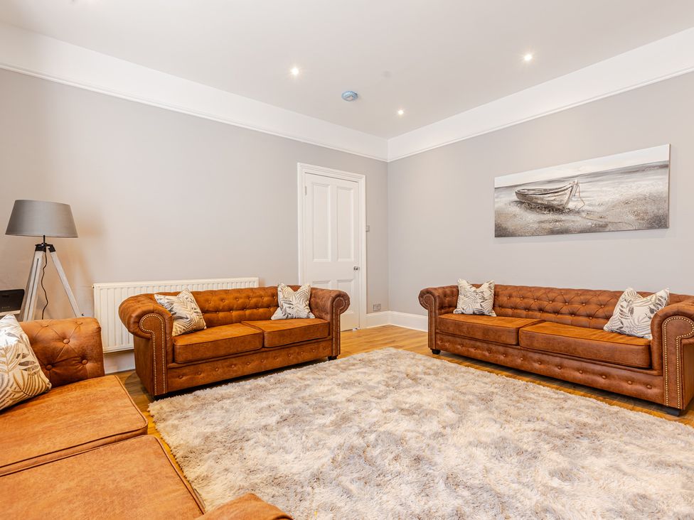 A living room with brown sofas and a rug at Palm Villa in Torquay