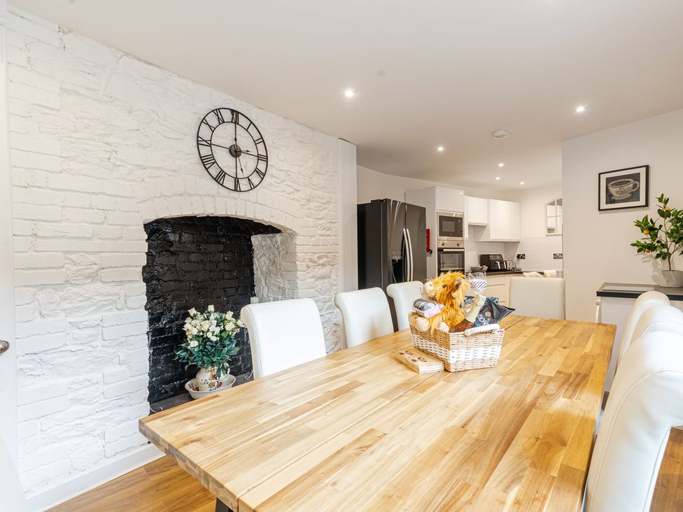 A kitchen with a dining table and wooden chairs at Palm Villa in Torquay