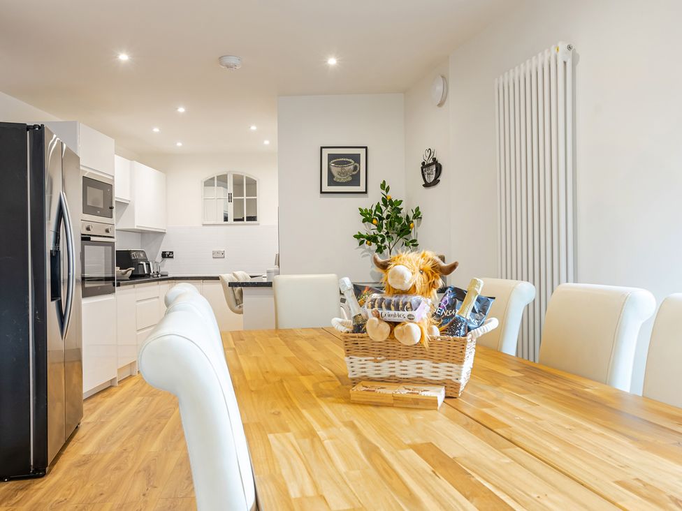 A kitchen with a dining table and refrigerator at Palm Villa in Torquay
