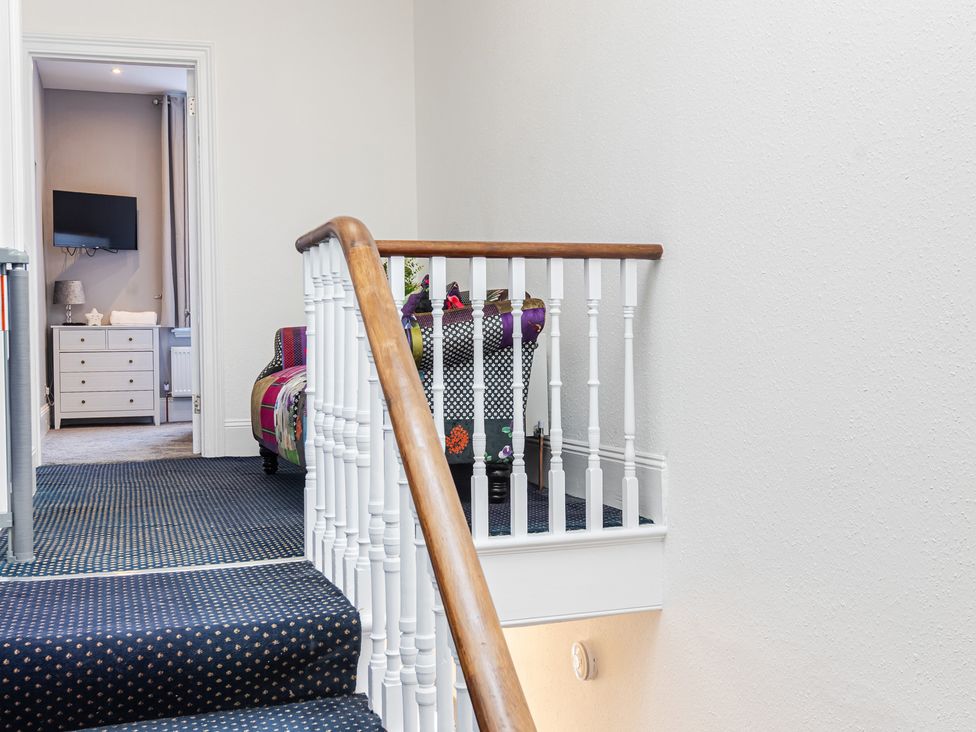A staircase with a handrail leading to a hallway at Palm Villa in Torquay