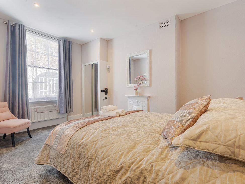 A bedroom with a bed and a chair at Palm Villa in Torquay