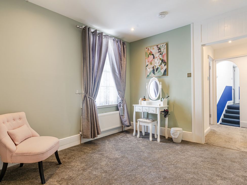 A bedroom with a vanity table and a chair at Palm Villa in Torquay