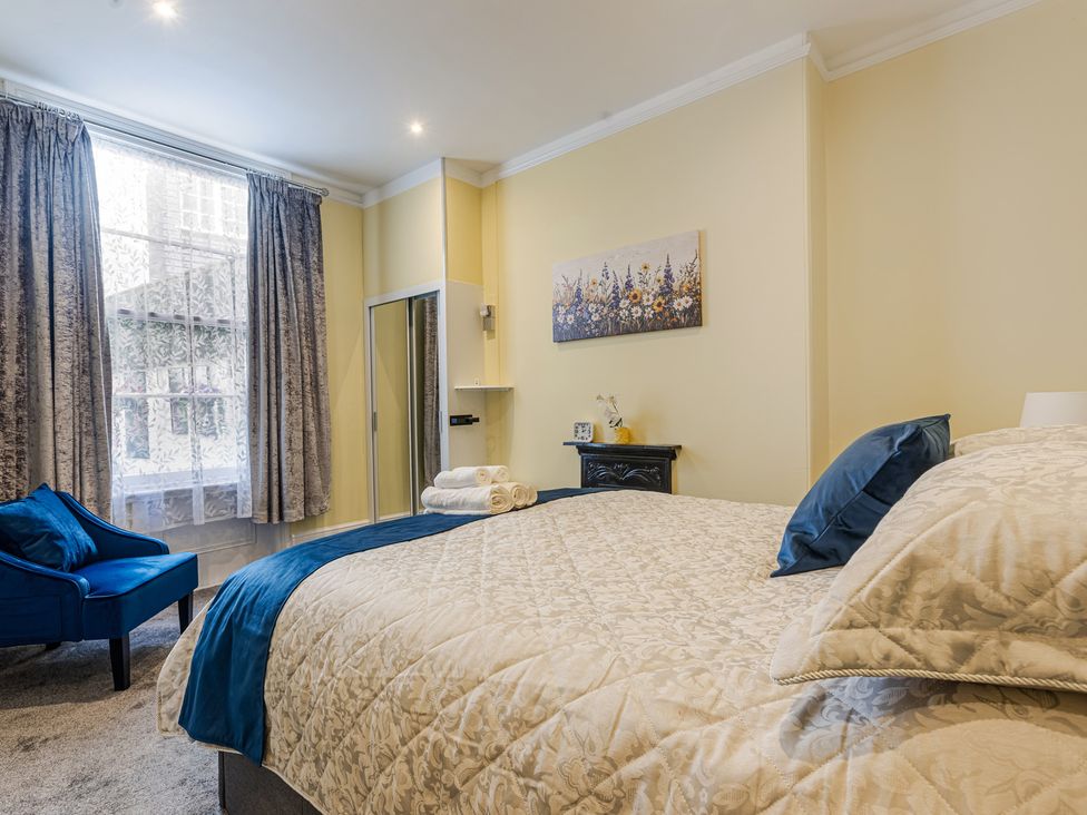 A bedroom with a bed, chair, and mirror at Palm Villa Torquay
