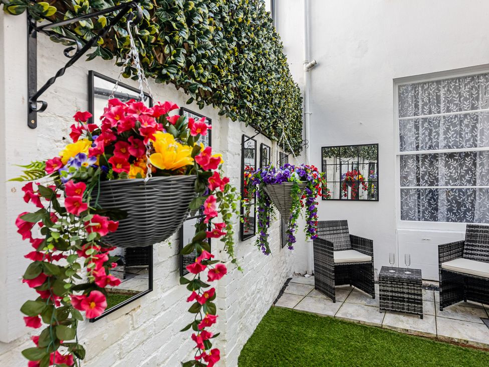 A garden with flower baskets and seating at Palm Villa in Torquay