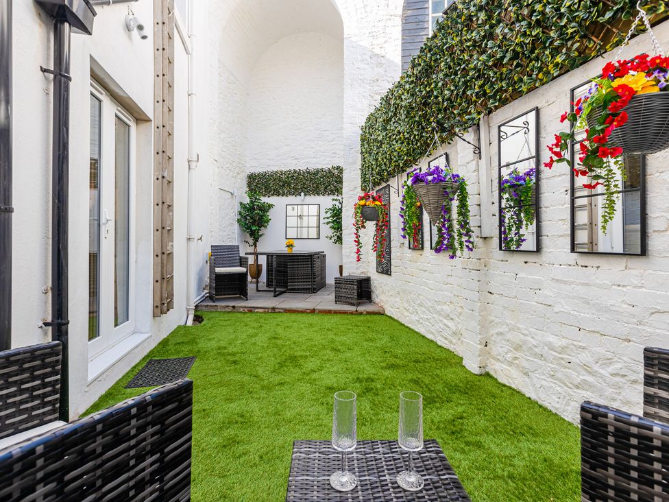 A garden with seating area and artificial grass at Palm Villa in Torquay