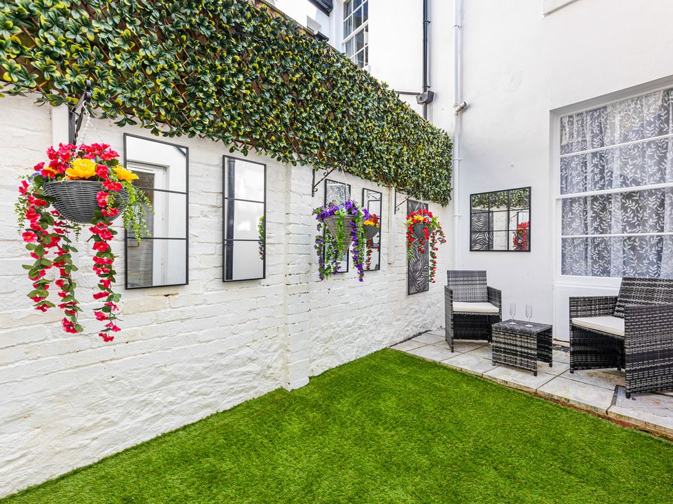 A garden with seating area and hanging plants at Palm Villa in Torquay