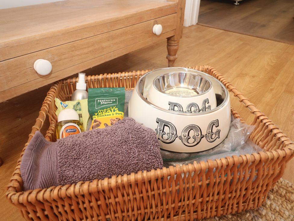 A basket with dog supplies including a bowl, towel, and treats at Yonde View in Camborne