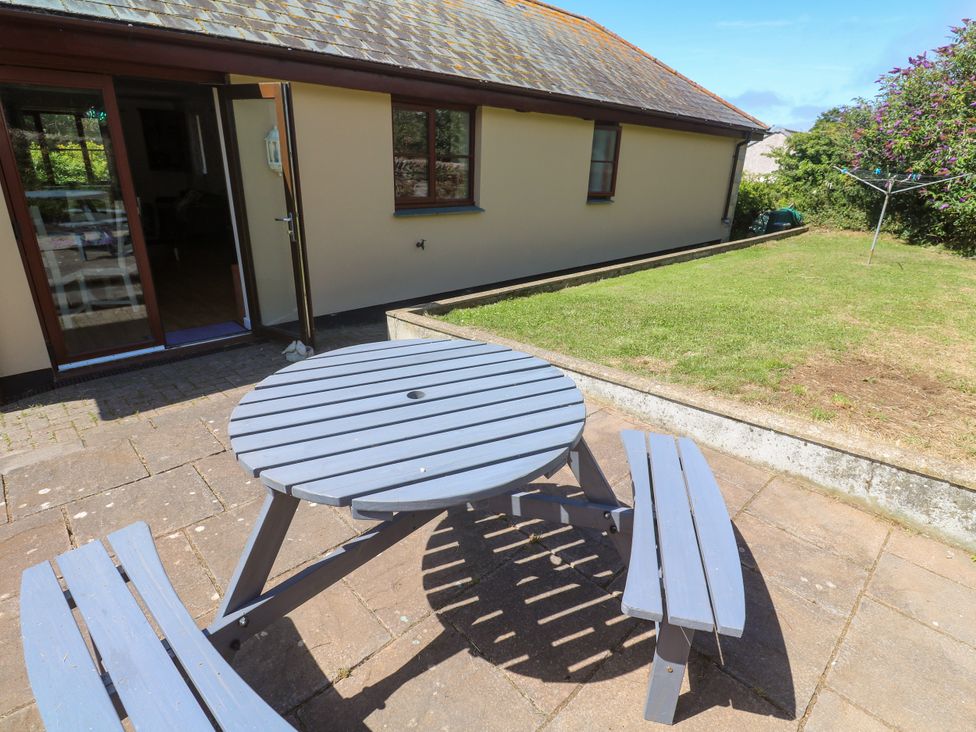 A table and benches on a patio in the garden at Yonde View in Camborne